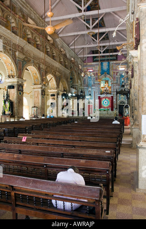 I credenti solitaria riverenti pregando nella navata riccamente ornato di Santa Cruz Basilica. Fort Kochi, Fort Cochin, Kerala, India del Sud Foto Stock