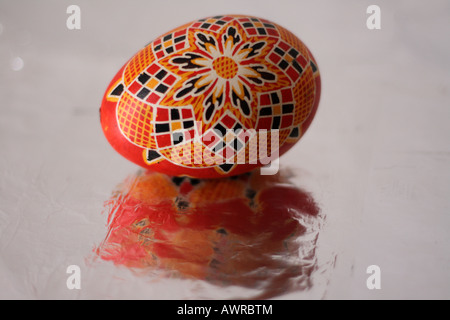 Un grande arancione tradizionale ceco uovo di Pasqua con il rosso e il nero modello geometrico riflette in lamina d'argento Foto Stock