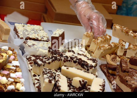 Una persona che serve una selezione di mano in casa dolci di pasticceria in un mercato degli agricoltori locali di fudge fayre fete isola di Wight Foto Stock