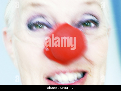 Donna matura indossando clown naso, close-up, offuscata Foto Stock