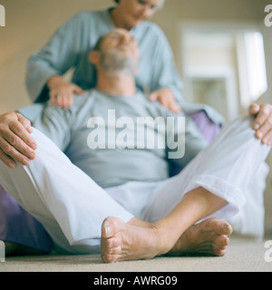 Senior uomo seduto, donna toccando le spalle a basso angolo di visione Foto Stock