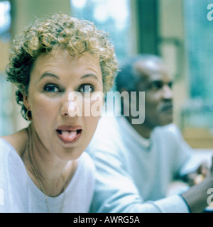 Donna spuntavano lingua, l'uomo in background Foto Stock