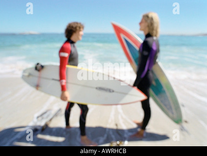 Due giovani uomini che tengono le tavole da surf sulla spiaggia, affacciati, sfocata. Foto Stock