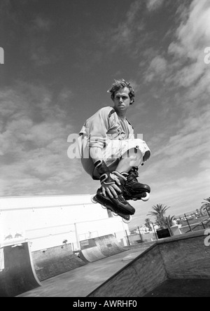 Giovane uomo su skateboard, saltando, mid-aria. Foto Stock