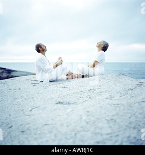 Coppia matura seduta su roccia, tra loro affacciate Foto Stock