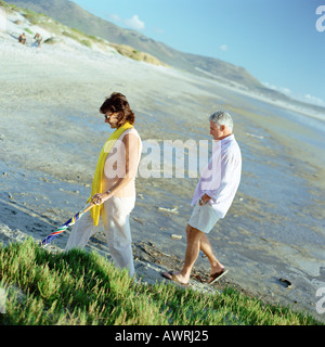 Coppia matura camminando sulla spiaggia, vista laterale Foto Stock