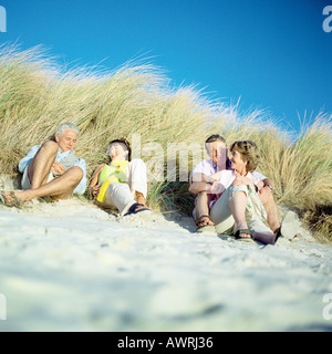 Due coppie mature seduto sulla spiaggia Foto Stock