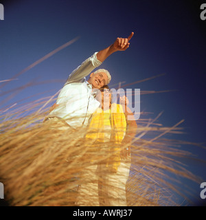 Coppia matura in piedi in erba alta, basso angolo di visione Foto Stock