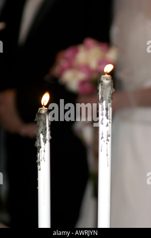 La sposa e lo sposo permanente al alter con candele di fronte al giovane Foto Stock