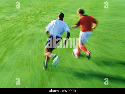 Due giocatori di calcio in esecuzione per la sfera, offuscata Foto Stock