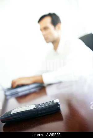 Telefono cellulare su imprenditore il desk, sfondo sfocato Foto Stock