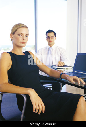 Imprenditore e donna seduta in ufficio, ritratto Foto Stock