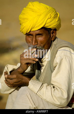 Uomo con turbante giallo fumare una sigaretta bidi, Pushkar, Rajasthan, India Foto Stock