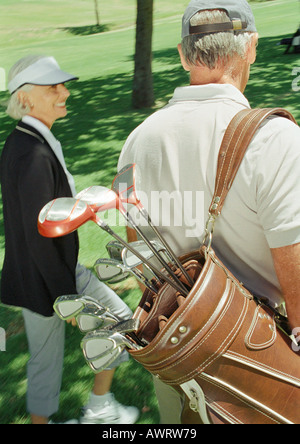 Due golfisti maturo, uno portante clubs, vista posteriore Foto Stock