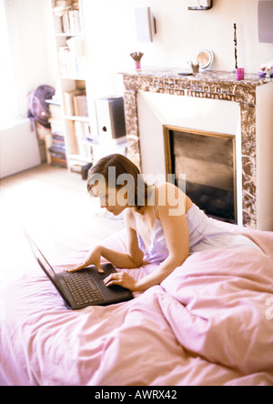 Donna che utilizza il computer portatile sul letto Foto Stock