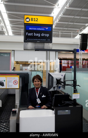 Un British Airways verificare nella persona dello staff manning un banco Fast Bag Drop dedicato all'Aeroporto di Londra Heathrow Terminal 5 Foto Stock