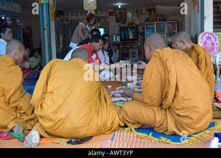 Seduti i monaci tailandesi accettare cibo da una famiglia dopo aver eseguito una cerermony per un deceduto recentemente membro della famiglia Foto Stock