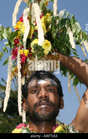 Adoratore indù che porta una pentola di metallo di acqua e curcuma dall'acqua ad un tempio in onore di Mariamman, India Foto Stock