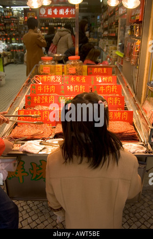 Dh Macao Cina giovane ragazza guardando spuntino cinese display di stallo shop carne essiccata