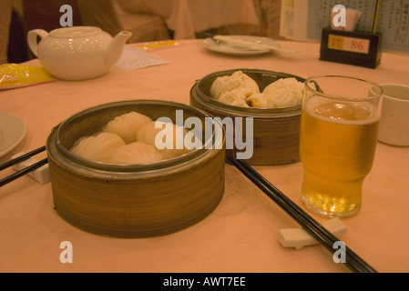 dh Chinese Dim Sum SHATIN HONG KONG Steamers Bamboo chopsticks bicchiere di birra e teiera chopstick pasto cestino cibo cina piatti cucina a vapore pranzo Foto Stock