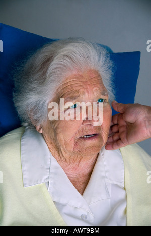 Assistenza agli anziani la vecchiaia donna triste apprensivi con consolante di toccare la mano di comunità infermiere caregiver toccando il suo volto Foto Stock