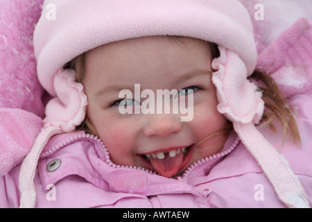 Una bambina di tre anni a giocare nella neve cercando di catturare i fiocchi di neve con la propria lingua Foto Stock