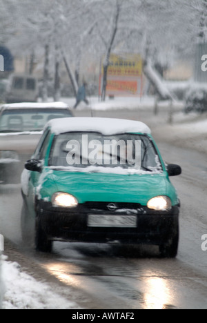 Vehicles Driving on a Snow and Ice Covered European Road in Winter Foto Stock