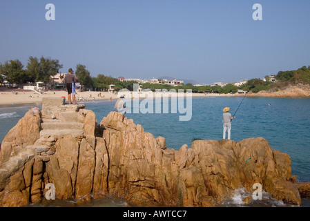 dh SHEK o HONG KONG Anglers pesca al largo delle rocce Isola Bay spiaggia costa Rod cina cattura pesce Foto Stock