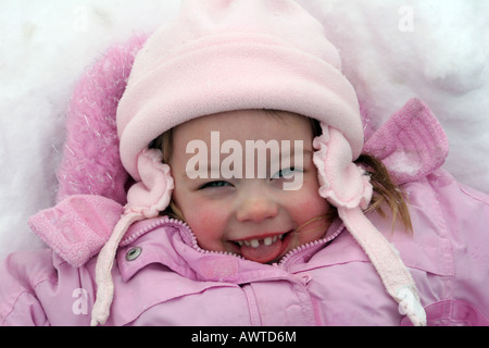 Una bambina di tre anni a giocare nella neve cercando di catturare i fiocchi di neve con la propria lingua Foto Stock