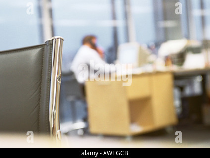 Imprenditore seduto alla scrivania parlando al telefono, sfocata. Foto Stock