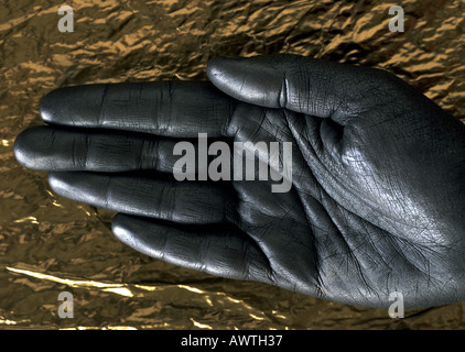 Verniciato argento mano contro la carta oro, close-up Foto Stock