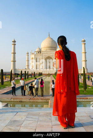 Una donna in un sari rosso davanti al Taj Mahal in Agra India Foto Stock