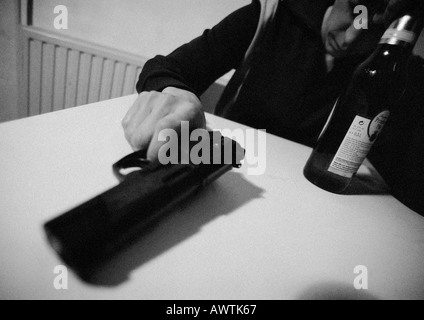 Uomo con pistola, la stretta di mano che tiene la pistola sul tavolo, close-up, b&W Foto Stock