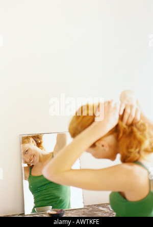 Donna che guarda la riflessione a specchio. Foto Stock
