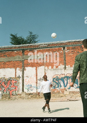 Gli uomini che giocano con il pallone da calcio nel contesto urbano Foto Stock