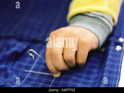 Bambino la mano che regge il perno di sicurezza, close-up Foto Stock