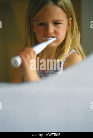 Bambina spazzolare i denti con spazzolino da denti elettrico, incentrata sulla riflessione a specchio Foto Stock