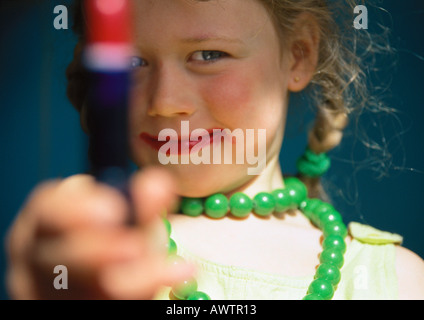 Bambina gioca dress up, tenendo fuori il tubo di rossetto Foto Stock