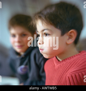 Ragazzo sbuffando guance, secondo boy guardando lui in background Foto Stock