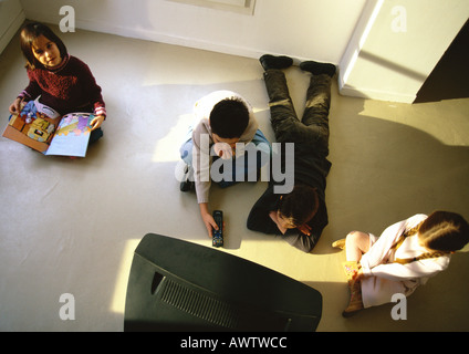 Ragazzi e ragazze seduti sul pavimento guardando la TV, ad alto angolo di visione Foto Stock