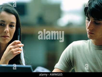 Donna tenendo pen accanto all uomo che guarda in basso Foto Stock