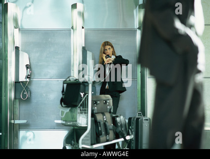 Imprenditrice parlando sul pubblico telefono a pagamento in aeroporto Foto Stock