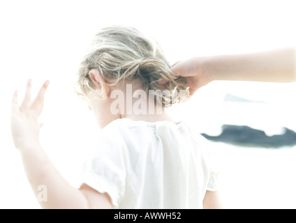 Toccando la mano del bambino capelli, vista posteriore, offuscata Foto Stock