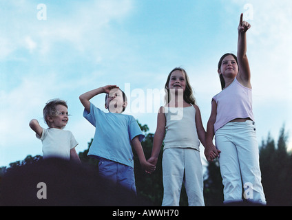 I bambini tenendo le mani all'aperto, uno rivolto uno sguardo di schermatura, vista frontale Foto Stock