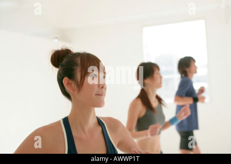 Due giovani donne e uomini che esercitano in ambienti interni Foto Stock