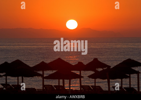 Bellissima alba in Roquetas de Mar in Spagna con paglia ombrelloni sulla spiaggia Foto Stock