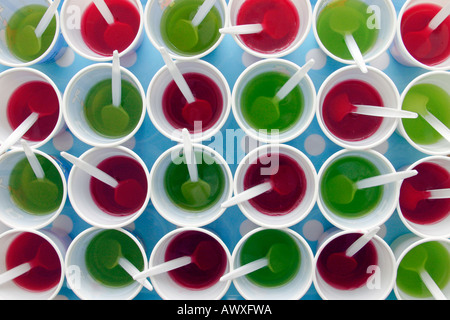 Il rosso e il verde jelly impostato in bicchieri di plastica su un vassoio in preparazione per una festa per i bambini Foto Stock