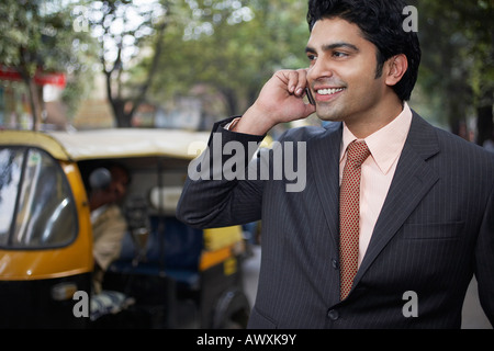 India, uomo d affari utilizzando il telefono cellulare su strada Foto Stock