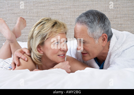Di mezza età giovane sdraiato sul letto a parlare Foto Stock