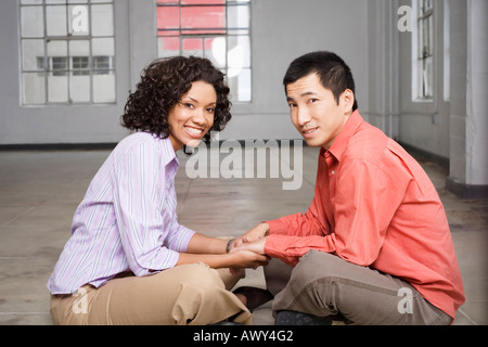 Giovane seduto sul pavimento tenendo le mani Foto Stock